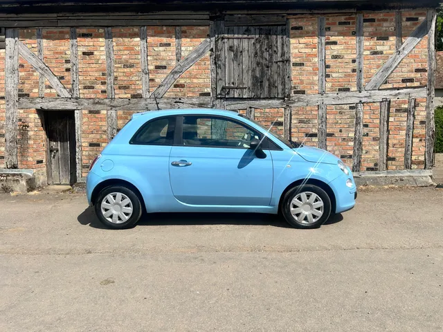 A pale blue Fiat 500 in profile